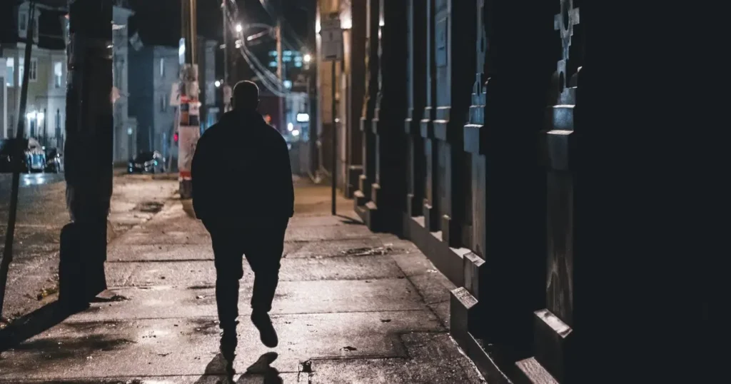 Man walking alone down a street at night, taking a break before talking to his wife